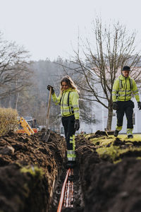 Male and female workers laying cables in trench