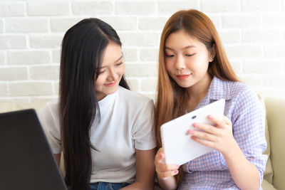 Beautiful young woman using smart phone in laptop