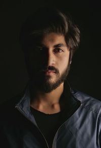 Portrait of young man against black background