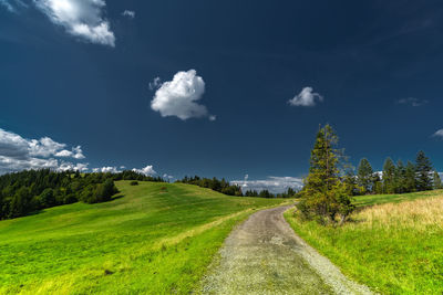 Empty road amidst field against sky