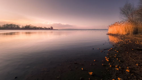 Scenic view of lake against sky at sunset