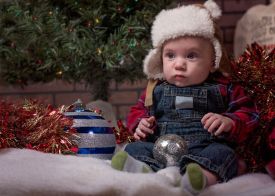 Close-up of cute boy sitting in christmas tree