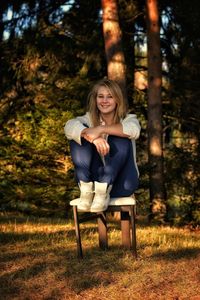 Portrait of young woman sitting in park during autumn