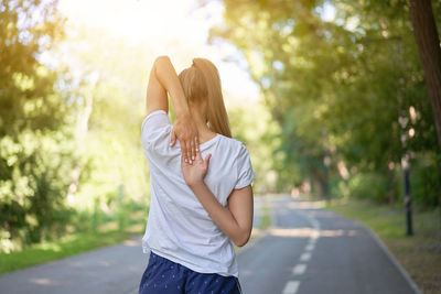 Full length of woman standing on road against trees