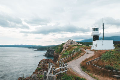 Lighthouse by sea against sky