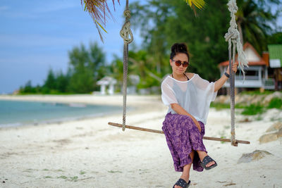 Young woman wearing sunglasses on beach against sky