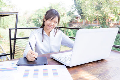 Woman using mobile phone while sitting on table
