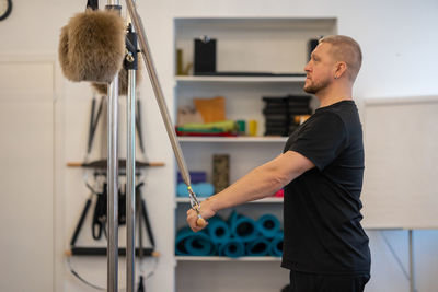 Male fitness pilates trainer shows exercises on special simulators. pilates stretch tables