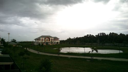 View of houses in calm lake against cloudy sky