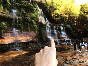 Cropped image of hand against waterfall