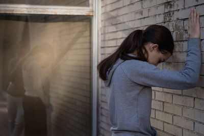 Portrait of young woman standing against wall