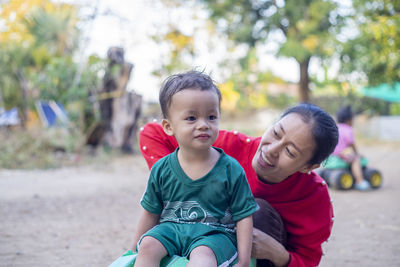 Smiling mother looking cute son in park