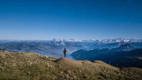 Man standing by mountains against clear blue sky