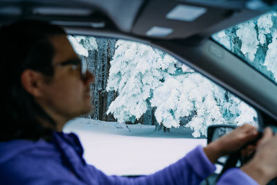 Man driving car on snowy mountain road in winter