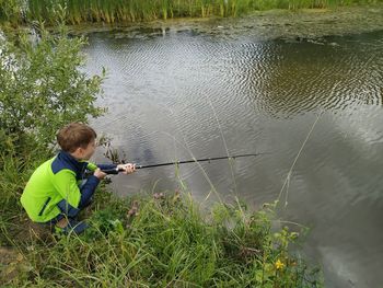 High angle view of boy fishing in lake