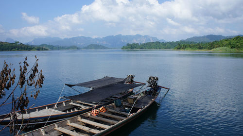 Boats in lake against cloudy sky