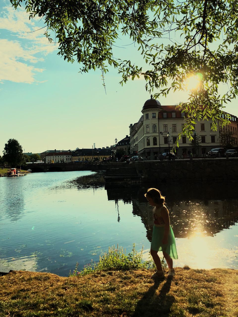 MAN STANDING BY LAKE AGAINST BUILDING