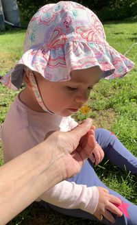 Midsection of woman holding hat on field