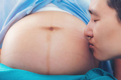 Close-up of man kissing pregnant woman stomach