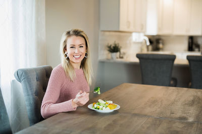 Portrait of a smiling young woman sitting at table