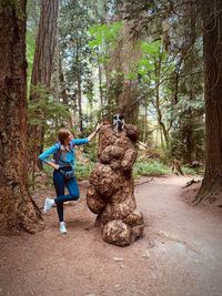 Side view of woman standing by tree in forest