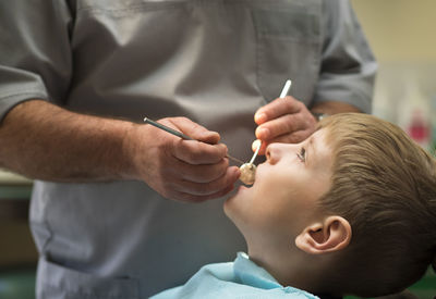 Midsection of male dentist examining boy at hospital