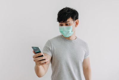 Midsection of man holding mobile phone against white background