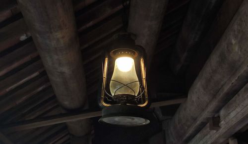 Low angle view of illuminated light bulb hanging from ceiling