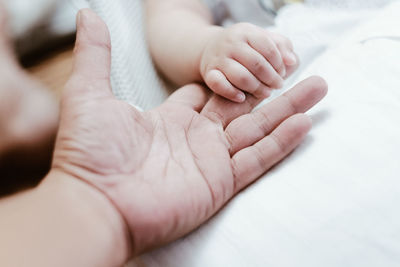 Cropped hand of baby on bed