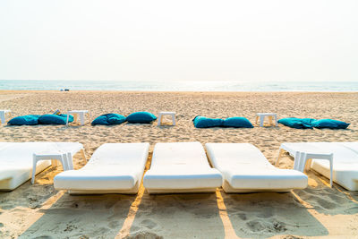 Deck chairs on beach against clear sky