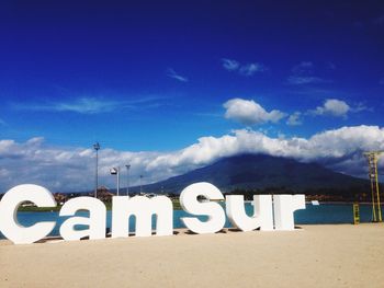 Information sign on beach against blue sky