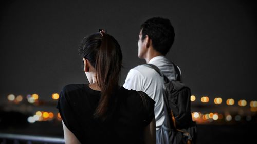 Rear view of couple standing against sky at night