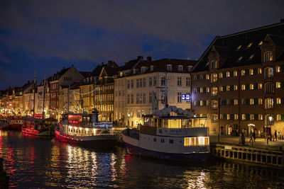 Canal amidst illuminated buildings in city at night