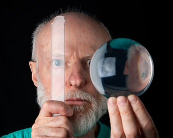 Close-up portrait of man holding glass over black background