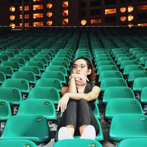 Full length of young woman sitting at stadium