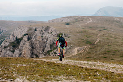 Rear view of man riding bicycling on mountain against sky
