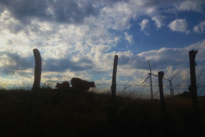 Fence on field against cloudy sky