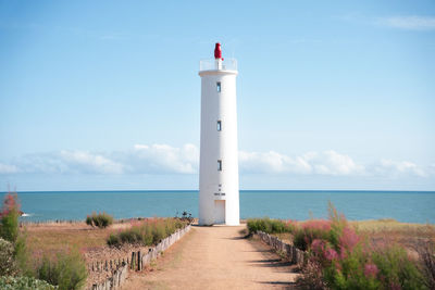 Lighthouse by sea against sky