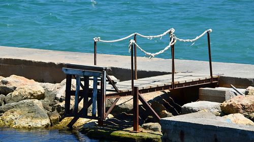 Deck chairs by sea against blue sky