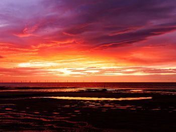 Scenic view of sea against dramatic sky during sunset