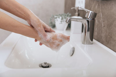 Cropped hands washing hand in sink