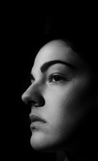 Close-up portrait of young woman against black background