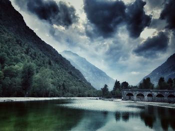 Bridge over river by mountains against sky