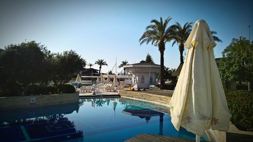 Panoramic view of temple in front of pond against clear blue sky