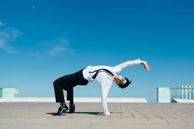 Low angle view of man jumping against sky