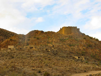 Built structure on landscape against cloudy sky