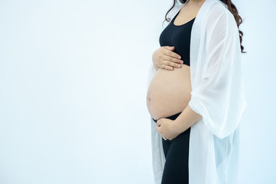 Midsection of woman standing against white background