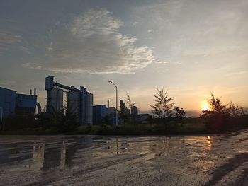 City street by buildings against sky during sunset