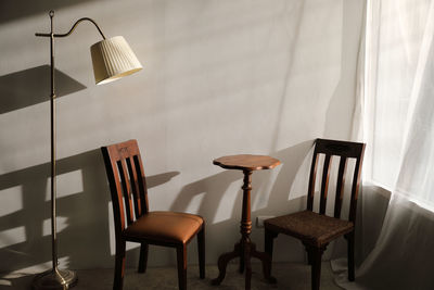 Empty chairs by table against wall at home