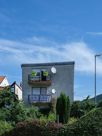 Low angle view of tree by building against sky